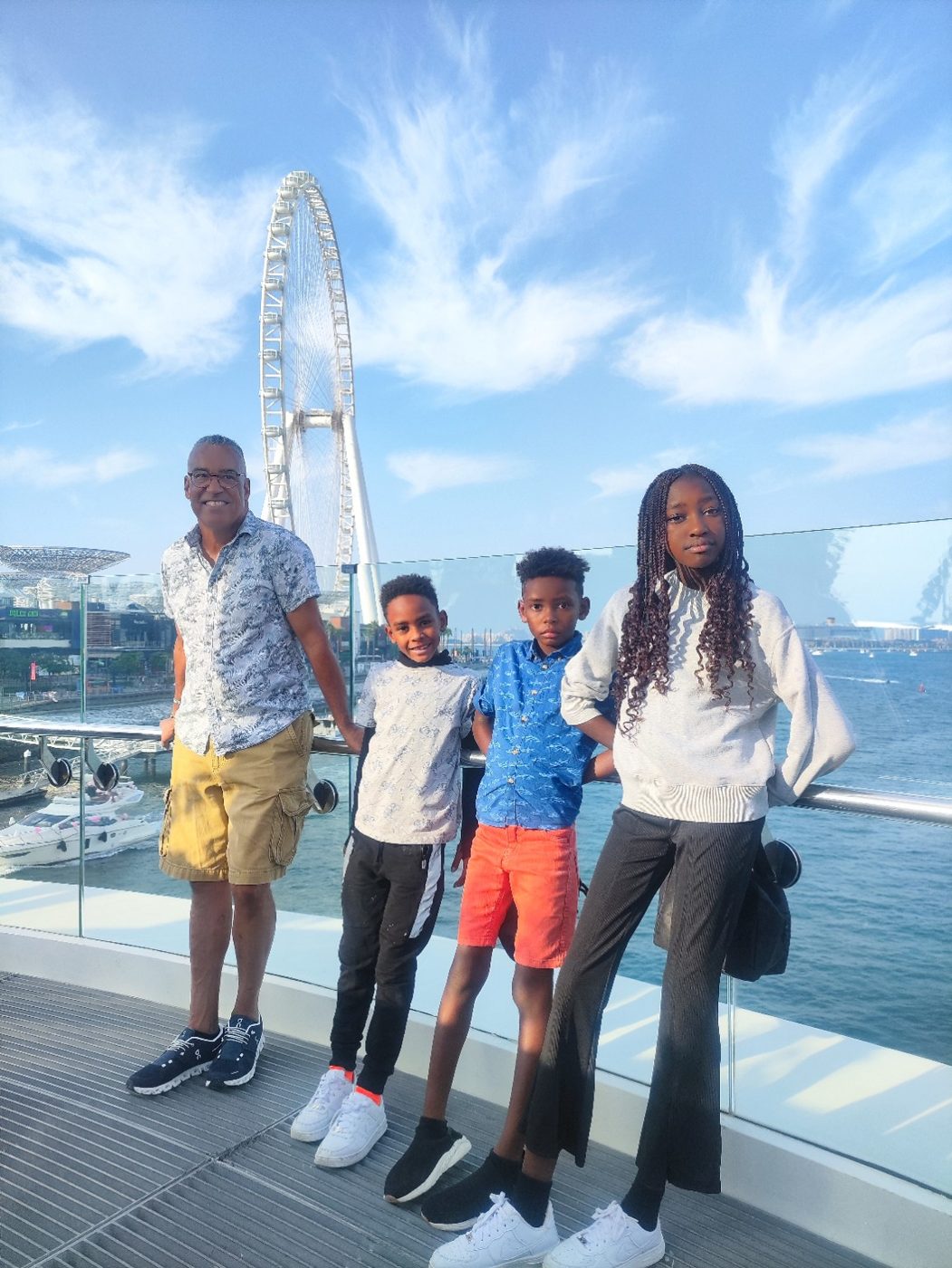 An adult and three children on the Bluewaters waterfront, with an observation wheel behind.