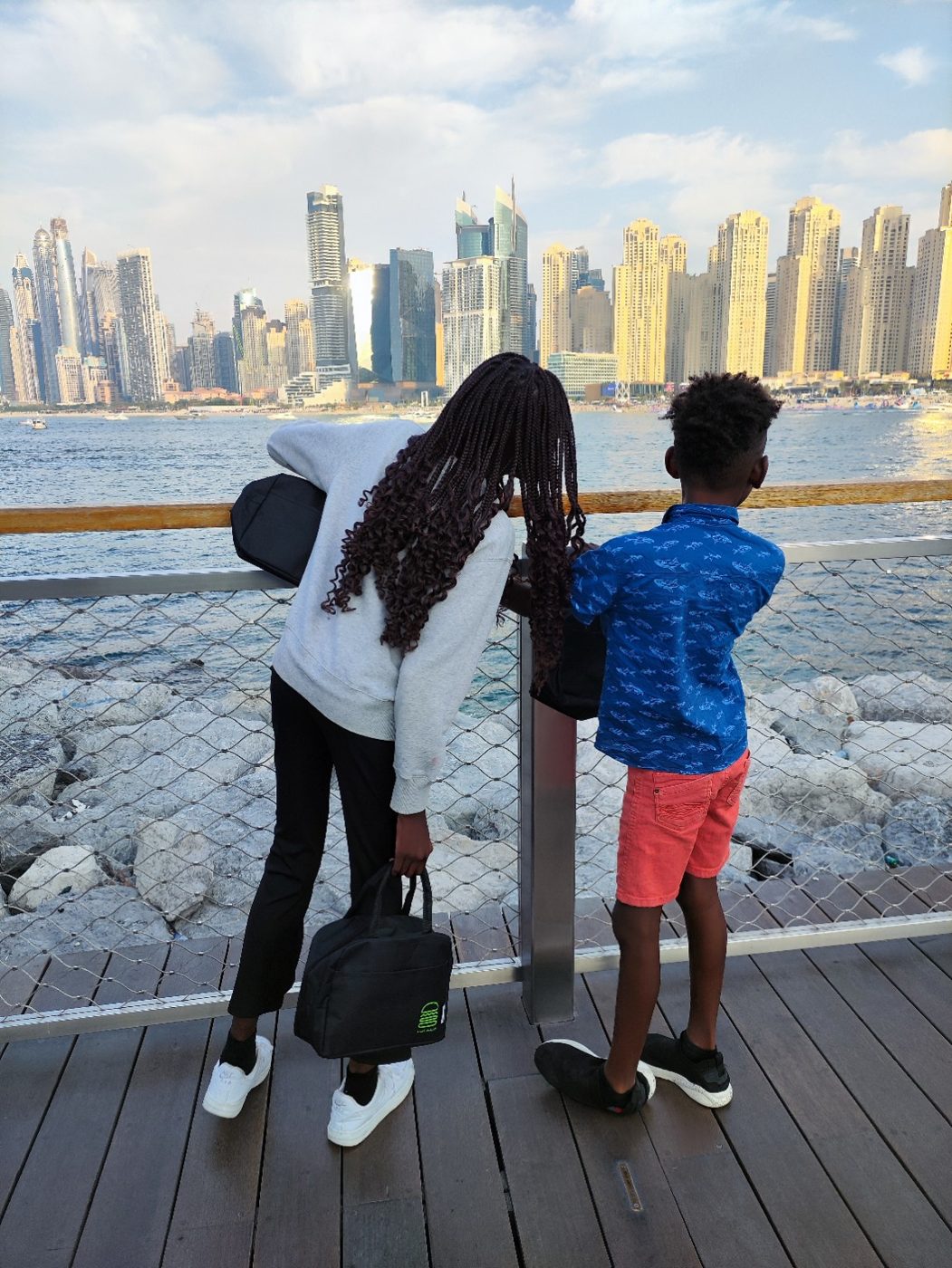 Two children looking across the water toward the JBR skyline.